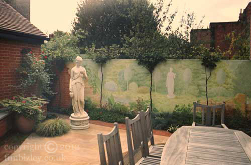 painted wall mural of shrubs and marble statues in a garden